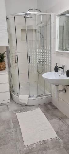 a white bathroom with a shower and a sink at Apartments Dora in Pag
