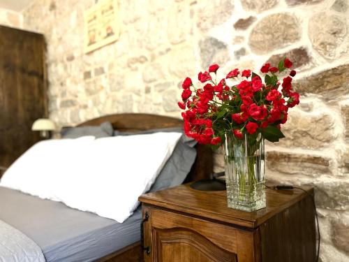 eine Vase roter Blumen auf einem Tisch im Schlafzimmer in der Unterkunft Una apartments in Kotor