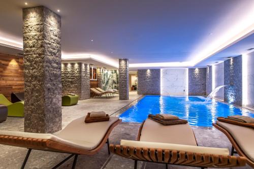 a swimming pool in a hotel with lounge chairs at Sassdei My Active Suite Hotel in Andalo