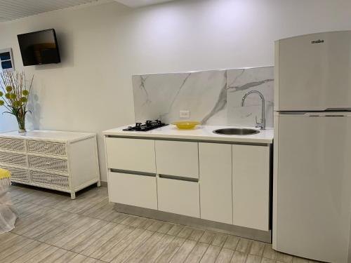 a white kitchen with a sink and a refrigerator at Tu Casita en Aruba in Palm-Eagle Beach