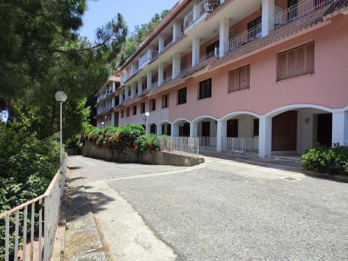 un bâtiment rose avec une clôture à côté d'une rue dans l'établissement a casa di Chiara, à Copanello