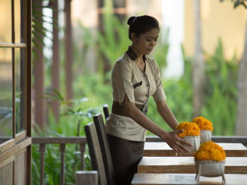 a woman standing next to a table with flowers at Alaya Dedaun Kuta in Legian