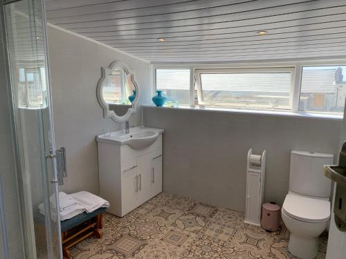 La salle de bains est pourvue d'un lavabo, de toilettes et d'un miroir. dans l'établissement Heather Glen. Six bedroom home near the sea., à Blackpool
