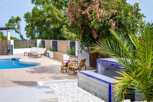 a backyard with a pool and chairs and a fence at Luxury Villa Alhambra Private Pool close to Sea and Centre in Benalmádena