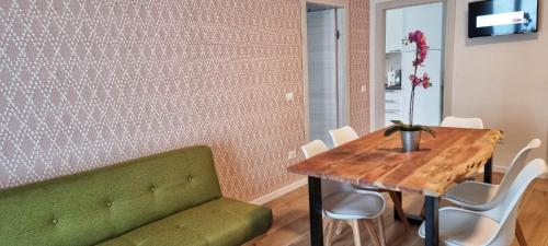 a dining room with a green couch and a wooden table at Casa Barcelli Sport & Family Apartments in Nago-Torbole
