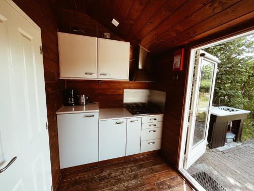 una pequeña cocina con armarios blancos y una ventana en Kampeerhuisje met veranda over de vijver, en Jubbega-Schurega