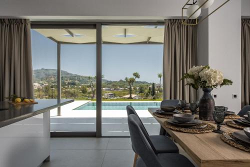 a dining room with a table and a view of a pool at Mystic Garden Villas in Zakynthos Town