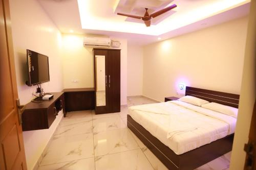 a bedroom with a bed and a television and a ceiling at Aman Residency in Thodupuzha