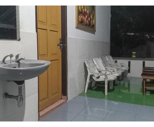 ein Bad mit einem Waschbecken und Stühlen in einem Zimmer in der Unterkunft Homestay Panrita Bone 