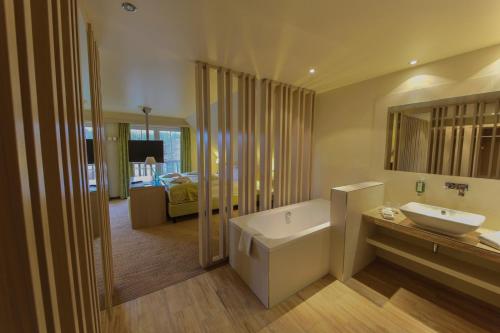 a bathroom with a white tub and a sink at Kur und Wellnesshaus Spreebalance, The Originals Relais (Relais du Silence) in Burg