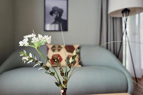 un vase avec des fleurs blanches sur une table à côté d'un canapé dans l'établissement Biohotel Alte Post, à Müllheim