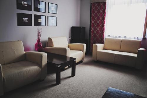 a living room with couches and chairs and a table at Hotel Pod Lwem in Elblag