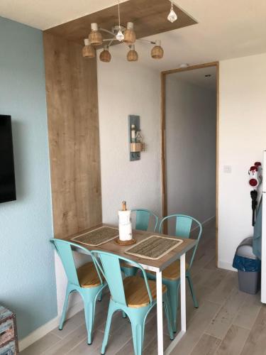 a dining room table with blue chairs and a light fixture at Ile du Cap Couladère - Vue magnifique lac marin - Baignoire Jaccuzi - Complexe piscine, sportif, animations in Le Barcarès