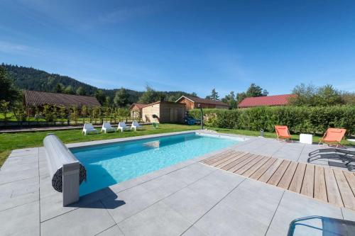 - une piscine avec un banc et des chaises dans la cour dans l'établissement Chalet du Bien-être 15p. Piscine,Spa, Hammam,Pétanque,Basket, à Gérardmer