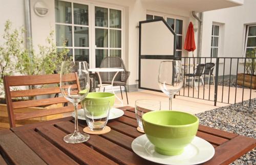 een houten tafel met twee groene kommen en wijnglazen bij Haus Meeresblick - Ferienwohnung Strandnah A 1.07 (Ref. 128675) in Baabe