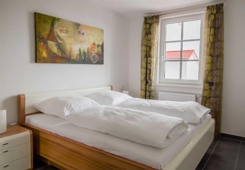 ein Bett mit weißen Laken und einem Gemälde an der Wand in der Unterkunft Haus Meeresblick - Ferienwohnung Suedost A 4.05 (Ref. 128720) in Baabe