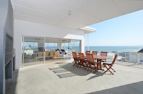 a table and chairs on a balcony with the ocean at 13 on Main in Yzerfontein
