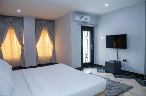 a bedroom with a white bed and a flat screen tv at Orange Roof Lodge in Abuja