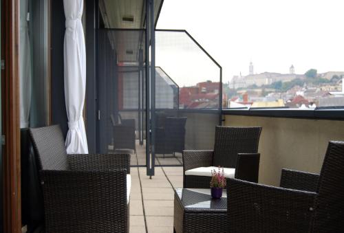 
a patio area with chairs, tables, and umbrellas at Hotel Regnum Residence in Budapest
