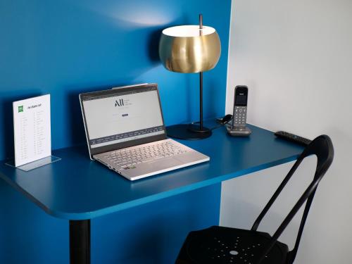 a laptop computer sitting on a blue desk with a lamp at ibis Styles Chartres Métropole in Chartres