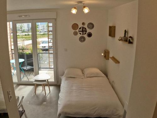 a bedroom with a bed and a table and a balcony at Studio Cosy Chambray-Les-Tours in Chambray-lès-Tours
