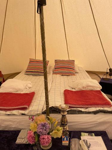 a bed with two pillows and a table with flowers on it at Naturglamping in Kristianstad