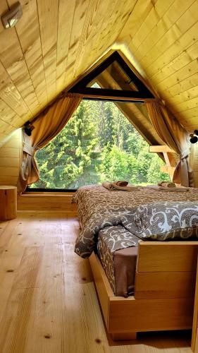 łóżko w pokoju z dużym oknem w obiekcie Brvnara Miris Bora w mieście Šljivovica