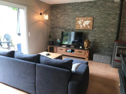 ein Wohnzimmer mit einem blauen Sofa und einem TV in der Unterkunft Maison au cœur du Pays Basque in Cambo-les-Bains