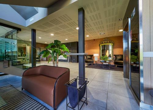 a lobby with a leather chair and a table at La Piconera Hotel & Spa in Ribadesella