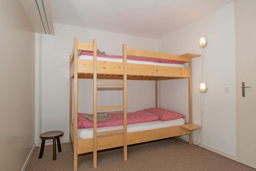 two bunk beds in a room with a stool at Ferienwohnung Schlegeli in Adelboden