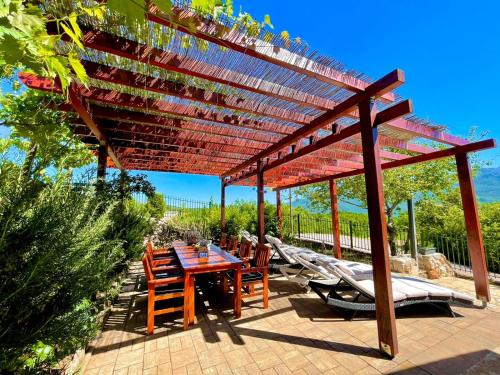 a wooden pergola with a table and chairs under it at Villa Sagosde with Swimming Pool and Mini Golf in Zagvozd