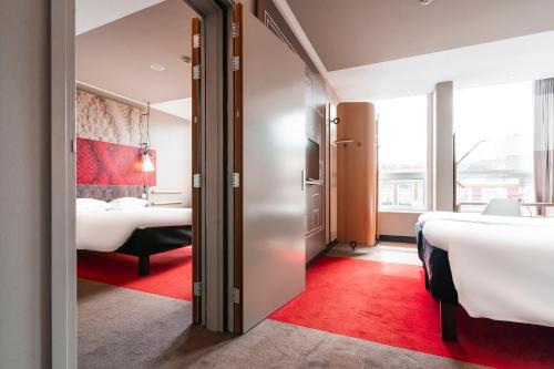 a hotel room with a large bed and a large window at Ibis Den Haag City Center in The Hague
