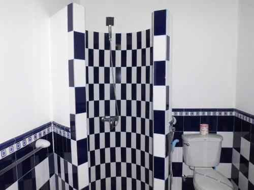 a bathroom with a toilet and a black and white tiled wall at Palace Mirissa in Mirissa