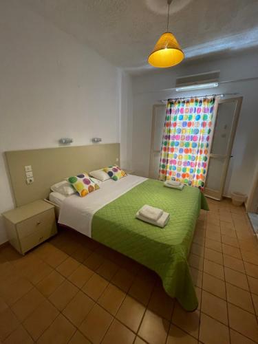a bedroom with a bed with a green blanket and a window at Matala View in Matala