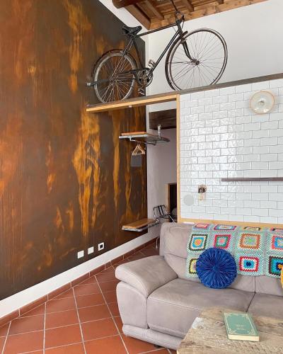 a bike hanging on a wall in a living room with a couch at Alkimia Smart Rooms in Ferrara