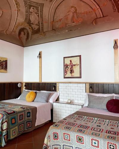two beds in a room with a ceiling at Alkimia Smart Rooms in Ferrara