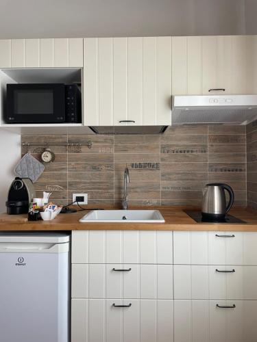 a kitchen with a sink and a microwave at Alkimia Smart Rooms in Ferrara