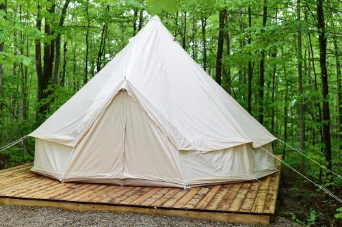 a tent sitting on a wooden platform in the woods at Grotto Getaway in Miller Lake