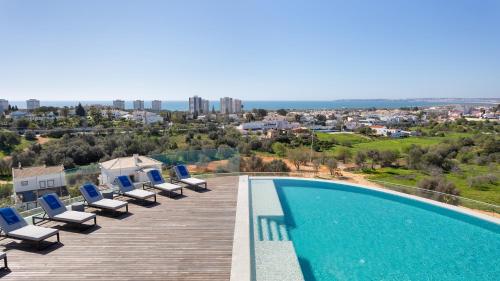 a swimming pool with lounge chairs on a wooden deck at Longevity Health & Wellness Hotel - Adults Only in Alvor