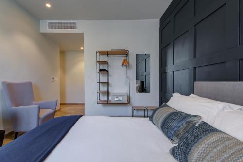 a bedroom with a large white bed and a chair at The Manoel Boutique Hotel in Valletta