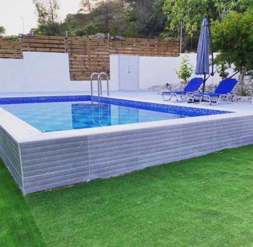 a swimming pool with two chairs and an umbrella at Irene Villa in Psinthos