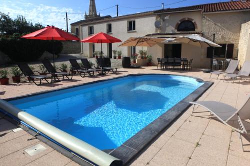 a blue swimming pool with chairs and umbrellas at Chambres d'hôtes La Fontaine! in Saint-Seurin-de-Cadourne