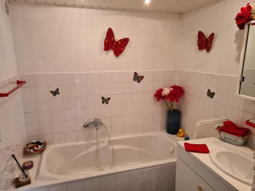 y baño con bañera, lavabo y mariposas en la pared. en Le Puy d'Ance, en Chastreix