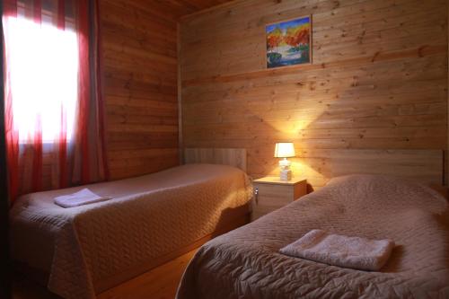 due letti in una stanza con pareti in legno e una finestra di Cottage Woodside a Mestia
