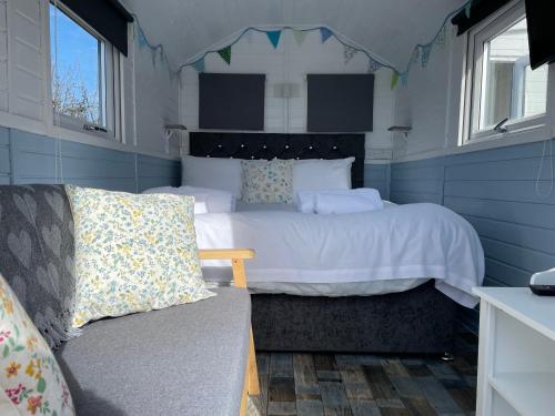a bedroom with a large bed and a couch at Estuary View - Cosy Shepherds Hut in Kingsbridge