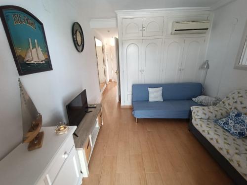 een woonkamer met een blauwe bank en een tv bij Apartamento en Cala de Finestrat in Cala de Finestrat