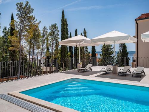 a swimming pool with two umbrellas and two chairs at Apartments Prkačin in Starigrad-Paklenica