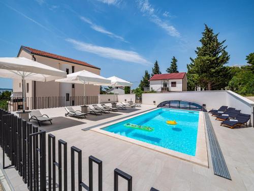 a swimming pool with chairs and a house at Apartments Prkačin in Starigrad-Paklenica