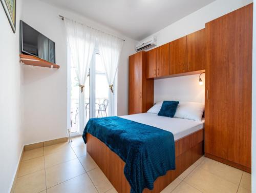 a bedroom with a bed with a blue blanket on it at Apartments Prkačin in Starigrad-Paklenica