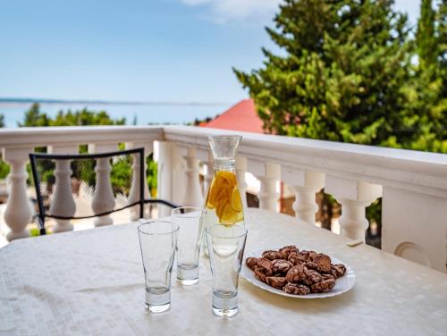 a table with two glasses and a plate of food at Apartments Prkačin in Starigrad-Paklenica